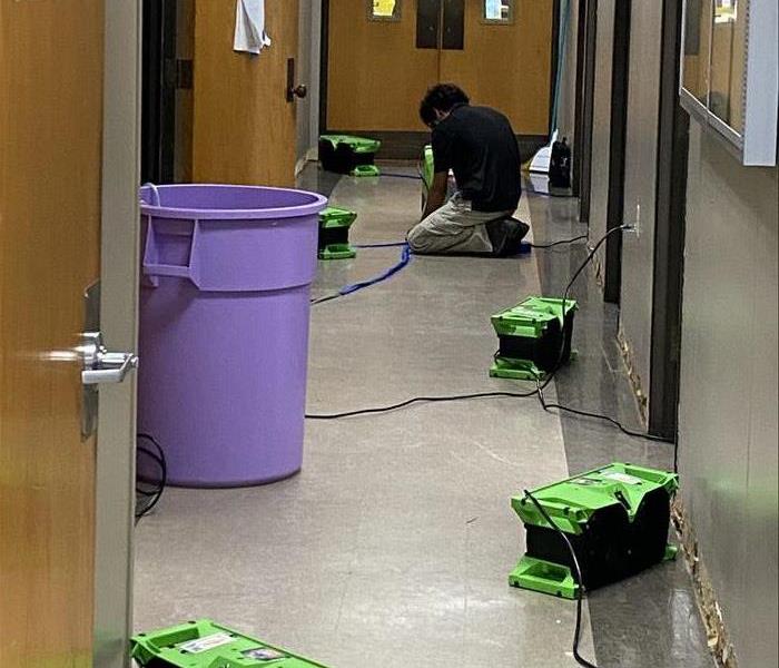 SERVPRO crew member deploying drying equipment in a commercial building to repair water damage